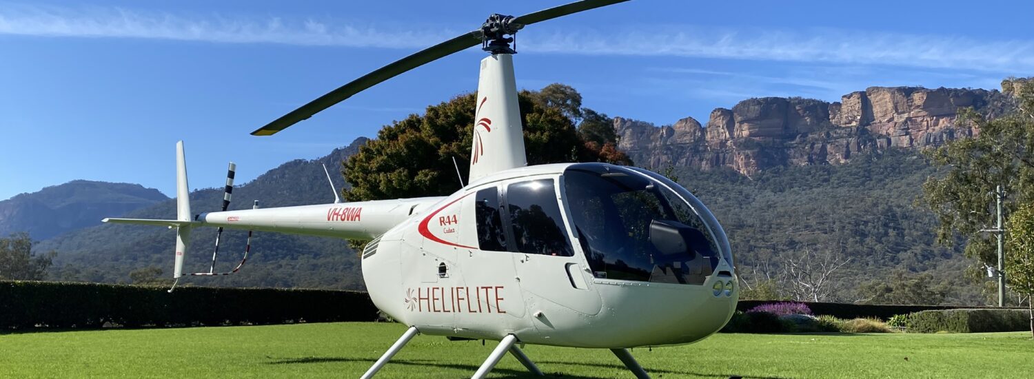 R44 Cadet White with Viper Red Parked | Leaders in Helicopter Sales and Service - Heliflite
